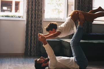 Wall Mural - Father and son during the morning spend time in the living room, flying games, morning fun and gymnastics