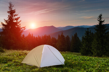 summer landscape. tourist tent in camp among meadow in the mountains at sunset. view of the dramatic