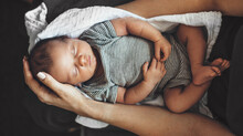 Upper View Photo Of A Newborn Baby Sleeping On His Parents Arms