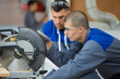 © auremar - young man being shown circular saw in factory