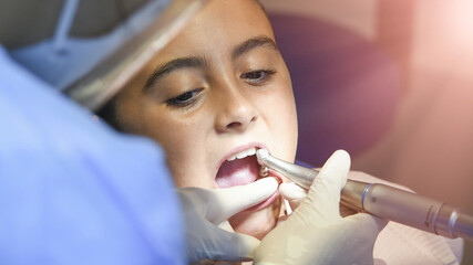 Canvas Print - Young caucasian female smiling while dentist in white latex gloves check condition of her teeth. baby girl in blue dental chair