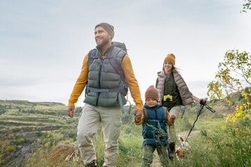 Poster - Three happy backpackers in warm casualwear and their cute pet enjoying trip