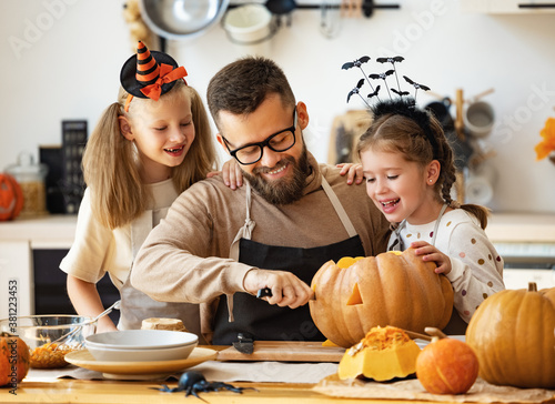 Fotomural happy family father and children prepare for Halloween by carving pumpkins at home in kitchen