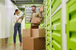 © Seventyfour - Full length portrait of modern couple using digital tablet while loading boxes into self storage container, copy space