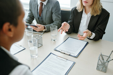 Hands of young businesswoman in formalwear over contract or financial documents