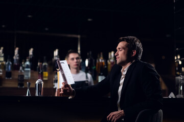 cute man reading the bar menu, sitting at the counter.