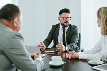 Wall Mural - Confident businessman in formalwear consulting young colleague at meeting