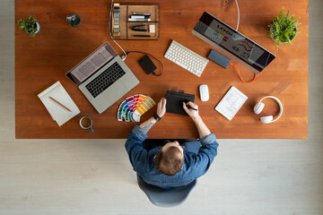 Wall Mural - Overview of young creative software developer drawing on tablet display by table