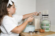 © Biddulph Photography - Cute Caucasian Girl Baking in the kitchen using a blue vintage tin