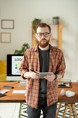 Wall Mural - Young bearded creative designer using tablet and stylus against computer monitor