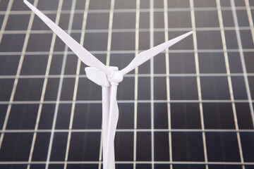 Wind power windmill in front of solar panels background