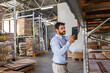 © Dusan Petkovic - Young attractive bearded supervisor standing next to shelves in warehouse and checking on goods while holding and looking at tablet.