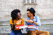 © Dusan Petkovic - Young cute multicultural hipster couple sitting outdoors and holding pizza.