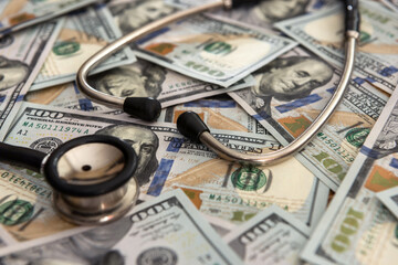 medical stethoscope lying on a lot dollar banknotes.