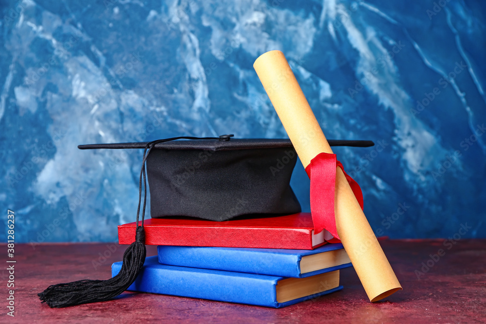 Graduation hat, diploma and books on color background