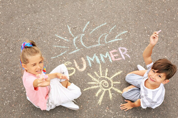 Little children drawing with chalk on asphalt