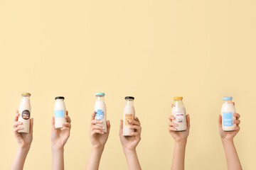 Female hands with bottles of vegan milk on color background