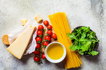 Wall Mural - Cooking pasta background. Raw ingredients for pasta with tomato sauce and cheese on gray background.