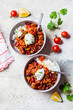 © vaaseenaa - Chili con carne with rice in gray bowl, top view. Beef stew with beans in tomato sauce with sour cream and rice. Traditional Mexican food concept.