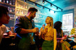 © Svitlana - Making night memorable. Young man leaning on bar counter, drinking cocktail and flirting with woman he just met. Young adults having drinks while chatting at the night club