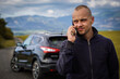 © Nataly - Portrait of young man standing in back of his broken car. He call the service to come and help him.