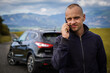 © Nataly - Portrait of young man standing in back of his broken car. He call the service to come and help him.