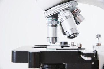 Using a biological microscope. Close-up of the microscope lens. Scientific research concept, using a microscope. Medical examinations, searching for bacteria, diseases, blood tests.