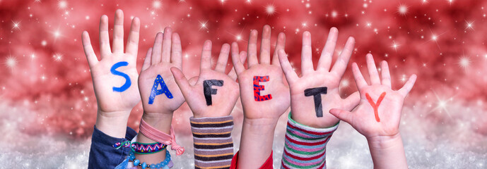 Children Hands Building Colorful English Word Safety. Red Snowy Christmas Winter Background With Snowflakes And Sparkling Lights