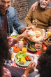 © LIGHTFIELD STUDIOS - Selective focus of man looking at african american woman holding bun on thanksgiving