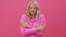 A Displeased Blonde Woman In A Pink Sweater Is Freezing Standing Isolated Over A Pink Background