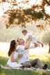 © Andriy Medvediuk - mom, dad lifts high his baby boy up mid air and looks at her smiling. Happy parents spending time playing with son in park on summer day. selective focus