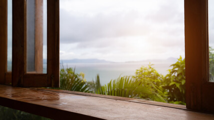 Wall Mural - Wood table top (Bar) with blur on green palm leaves or tree in tropical forest with sky and sea at background