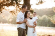 © Andriy Medvediuk - dad, mom hugging son outdoors in the park. The concept of summer holiday. Mother's, father's, baby's day. Family spending time together on nature. Family look. selective focus
