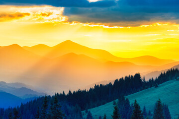 Wall Mural - Beautiful sunset in the mountains. Landscape with sun shining through orange clouds