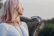 © Creatopic - silhouette of a young beautiful girl playing the saxophone at sunrise by the river, a woman in a long dress on the nature at sunrise relaxing, concept music