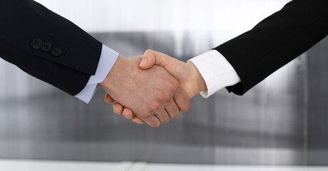 Businessman and woman shaking hands in office. Concept of handshake as success symbol in business