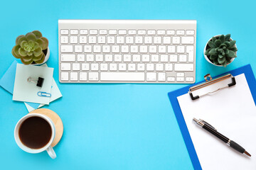 blue office desk background with smartphone with blank screen mockup, laptop computer, cup of coffee and supplies. Top view with copy space, flat lay.