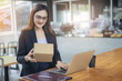 © Panumas - Startup on-line business entrepreneur SME, Businesswoman packing product in box and working with laptop at home office. SME e-commerce telemarketing concept