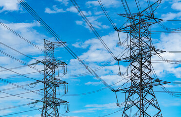 High voltage electric pylon and electrical wire against blue sky and clouds. Bottom view of electric pylon. High voltage grid tower with wire cable. Transmission lines on high voltage grid tower.