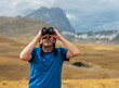 © trattieritratti - Hiker with binoculars observes birds in the mountains