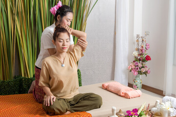 Wall Mural - Thai Masseuse doing massage for woman in spa salon. Asian beautiful woman getting thai herbal massage compress massage in spa.She is very relaxed.  Healthy Concept