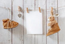 Children's Shoes For The First Steps, Small Brown Shoes In A Retro Style Hang On Clothespins With A Soft Toy And A Blank Sheet Of Paper, Free Space, Childhood Concept