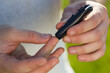 © Nana_studio - Man taking a blood sample with a lancet handle outside. Diabetes concept