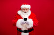 © deagreez - Portrait of his he nice attractive handsome cheerful cheery focused Santa using gadget 5g fast speed blog blogger post comment media isolated over bright vivid shine vibrant red color background