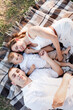 © Andriy Medvediuk - Mom, dad and little son lying on the blanket in the summer park. The concept of summer holiday. Mother's, father's, baby's day. Family spending time together on nature. Family look