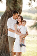 © Andriy Medvediuk - dad, mom hugging son outdoors in the park. The concept of summer holiday. Mother's, father's, baby's day. Family spending time together on nature. Family look. selective focus