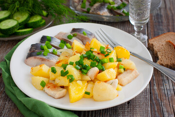 Wall Mural - fried potatoes with chicken fillet on a white plate with salted herring pieces, selective focus