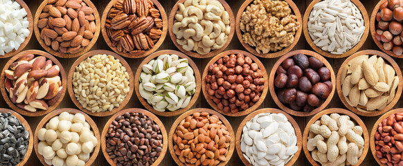Wall Mural - assorted nuts and seeds in wooden bowls, food background.