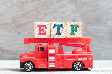 Sticker - Red fire truck hold letter block in word ETF (abbreviation of Exchange Traded Fund) on wood background