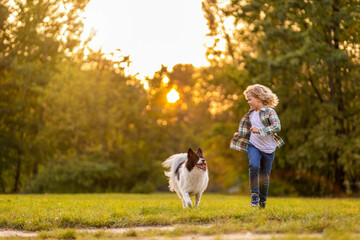 Little boy playing with his dog outdoors in the park
